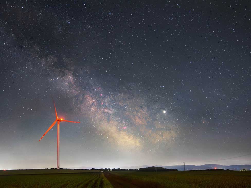 Night sky photo of a field and wind mill